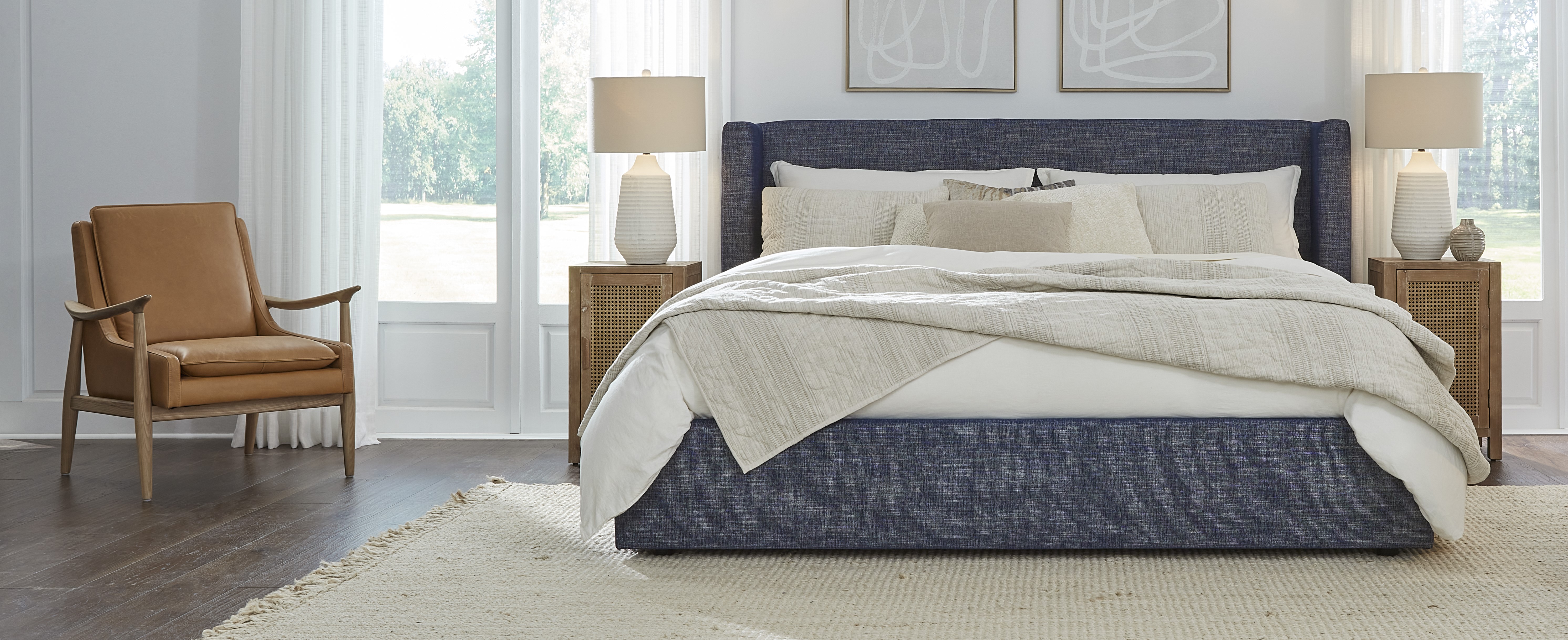 Kuka Home Furnishings Bedroom with navy blue fabric headboard and tan leather accent chair